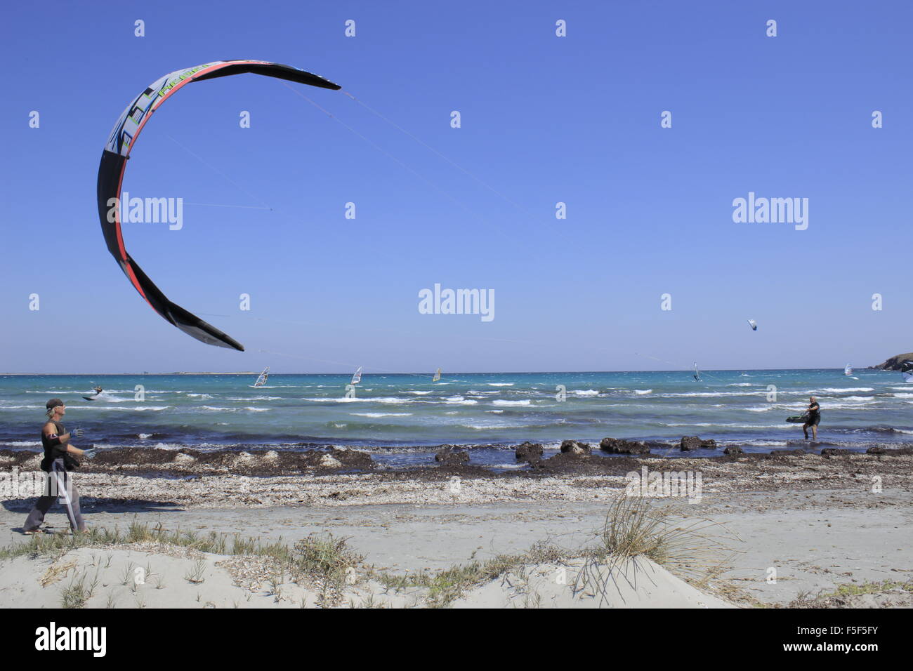 Parasurfer (in the sea) and helper landing a kite on Keros bay beach, Lemnos or limnos island, Greece. Stock Photo