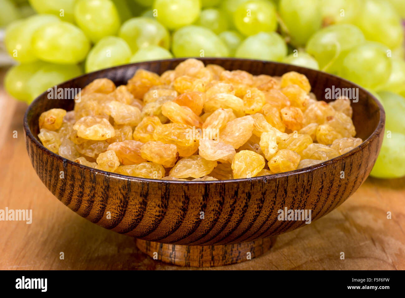 white seedless grapes and raisins sultanas in a wooden bowl Stock Photo