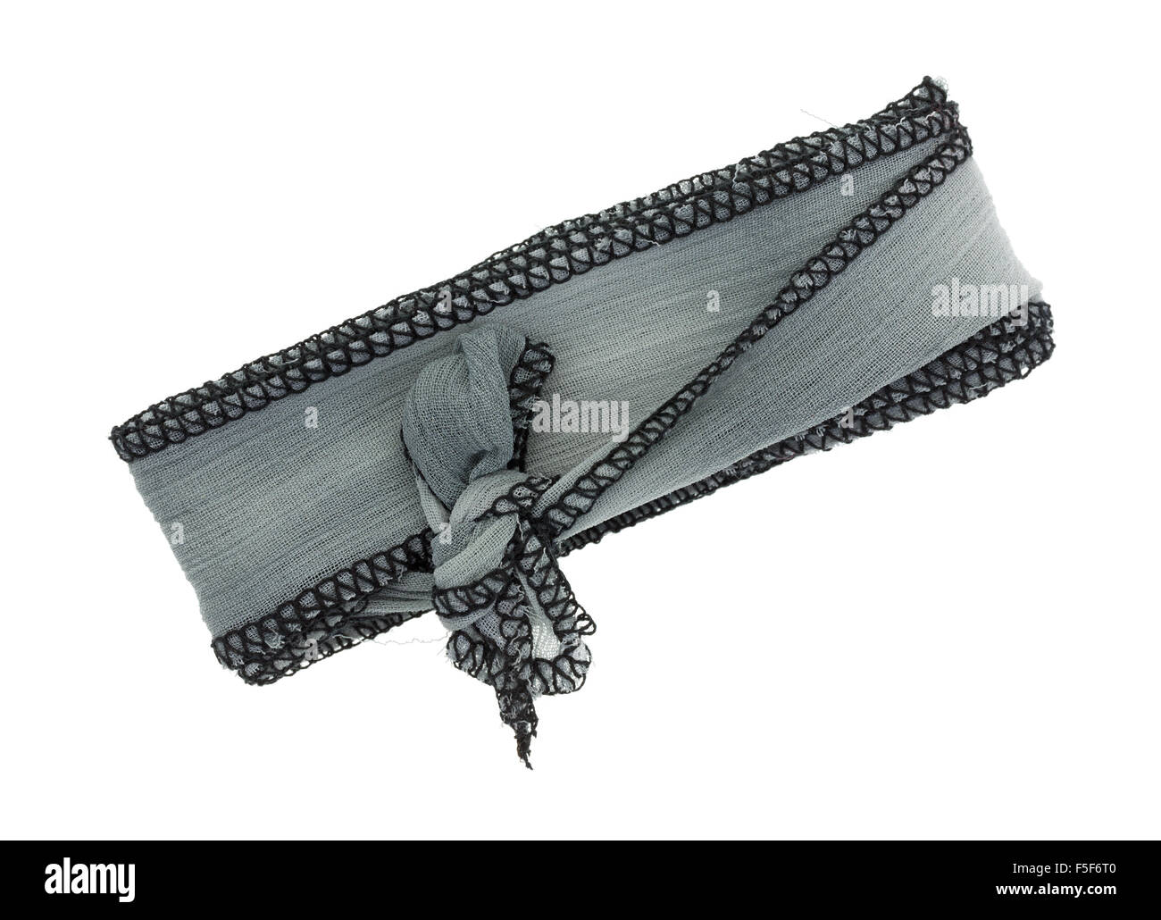 A small length of gray ribbon cloth with a binding stitch tied isolated on a white background. Stock Photo