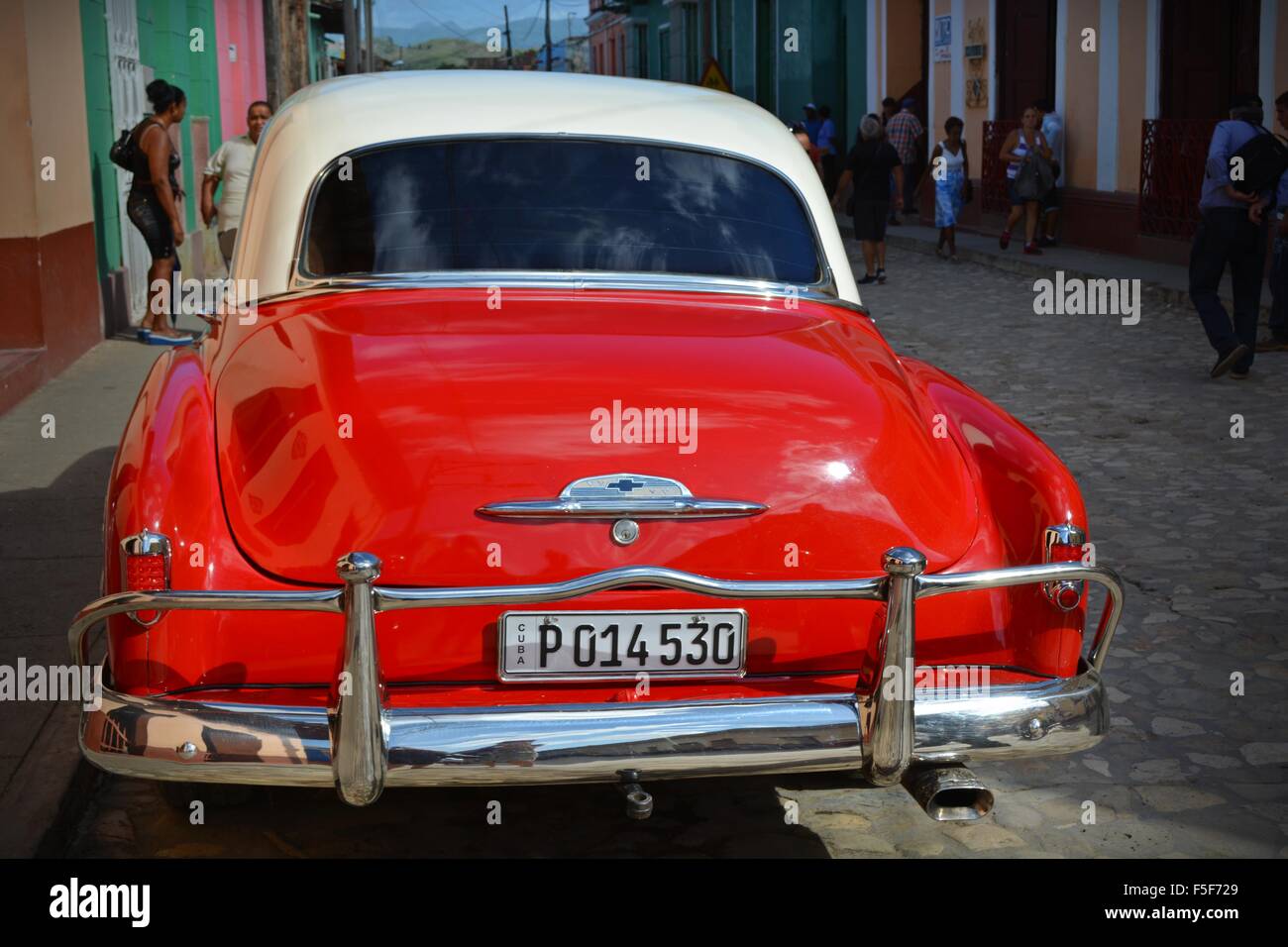 Vintage red and white car parked on a quiet street in Trinidad Cuba Stock Photo