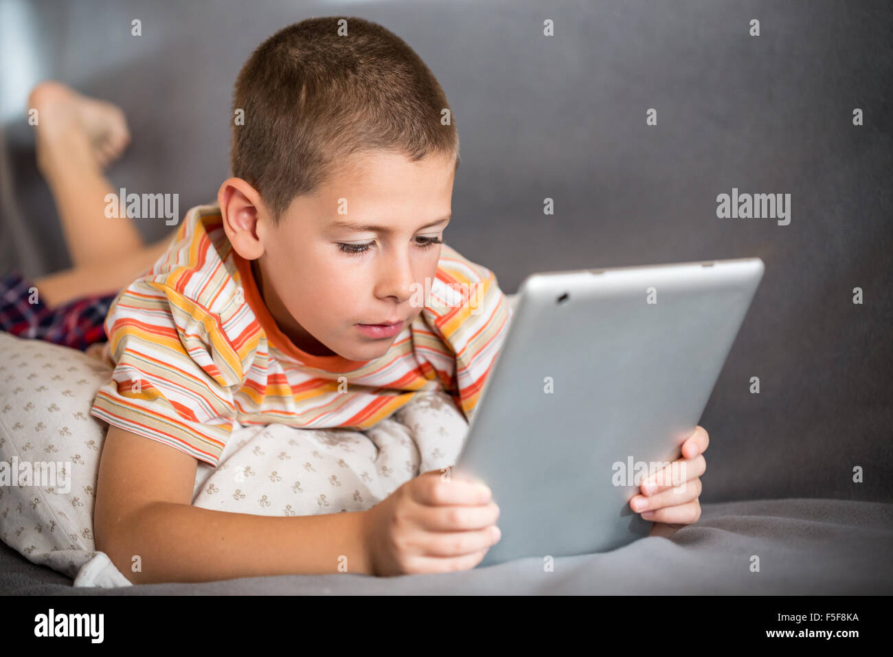 Little boy lying in bed and watch a story on touchscreen tablet Stock ...