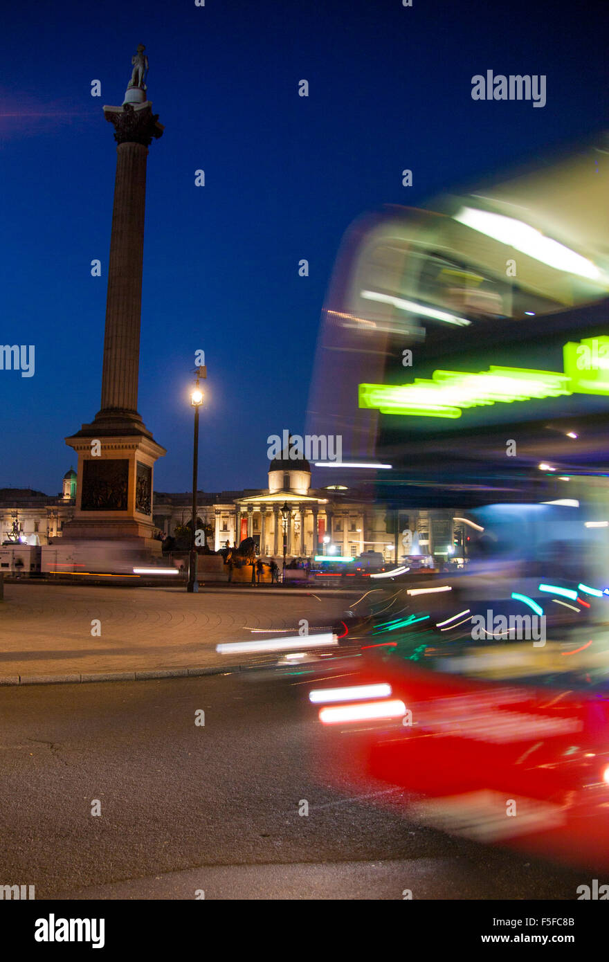 Trafalgar Square Nelson's Column and National Gallery at night with red London bus passing through with motion blur Stock Photo