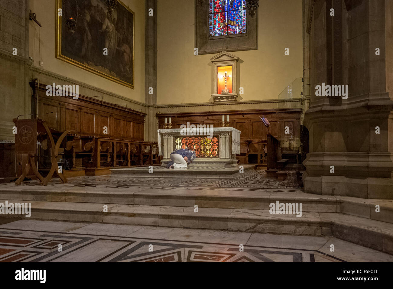 Woman kneeling and praying at the alter in a church Stock Photo