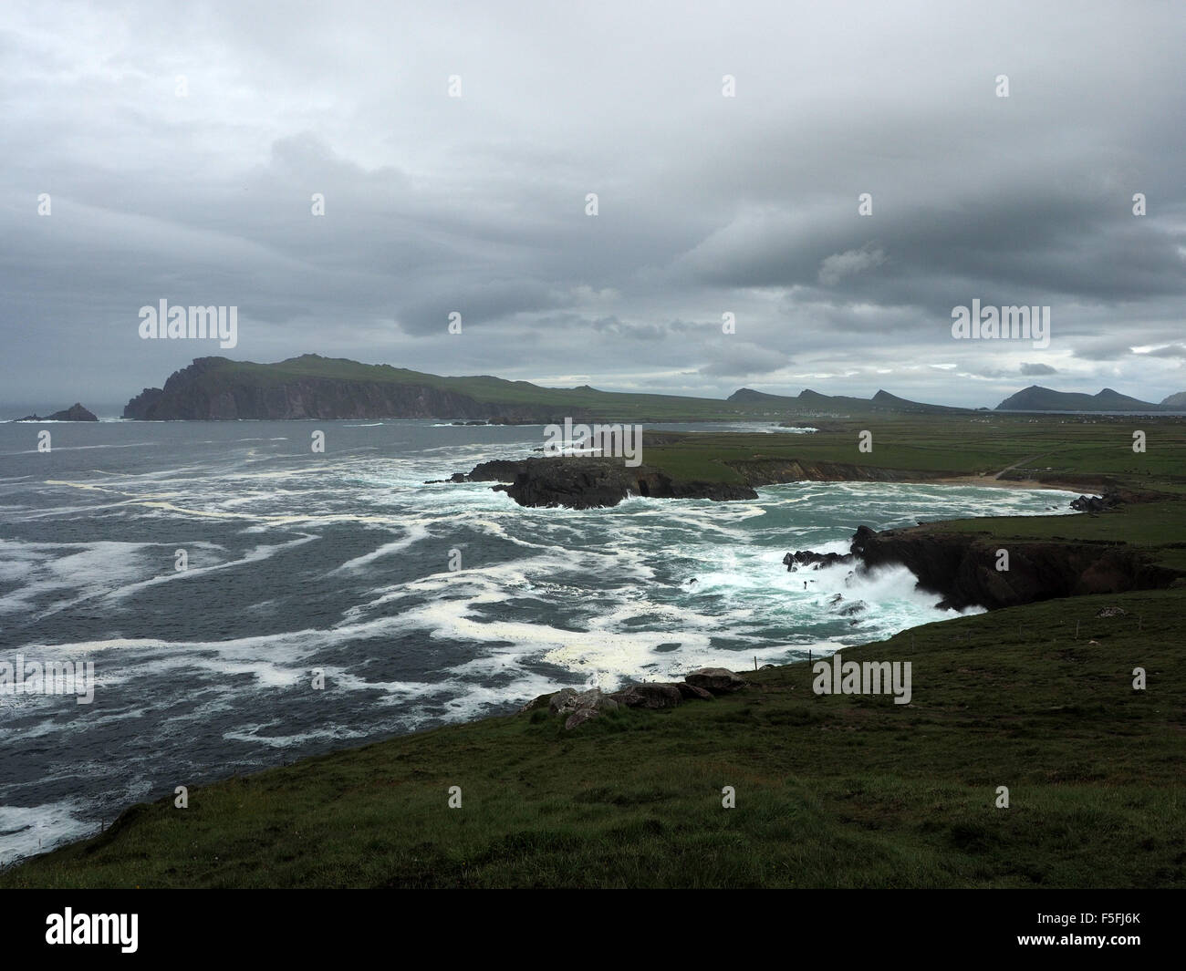 Turbulent sea waves crashing into bays and coves between Dunquin and  Ballyferriter on Dingle peninsula Ireland under dark sky Stock Photo