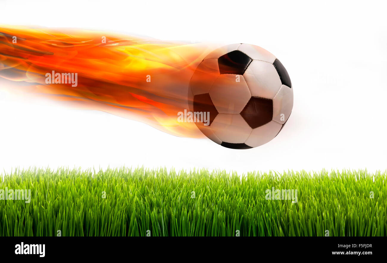 Smoking soccer ball on fire over green field. Stock Photo