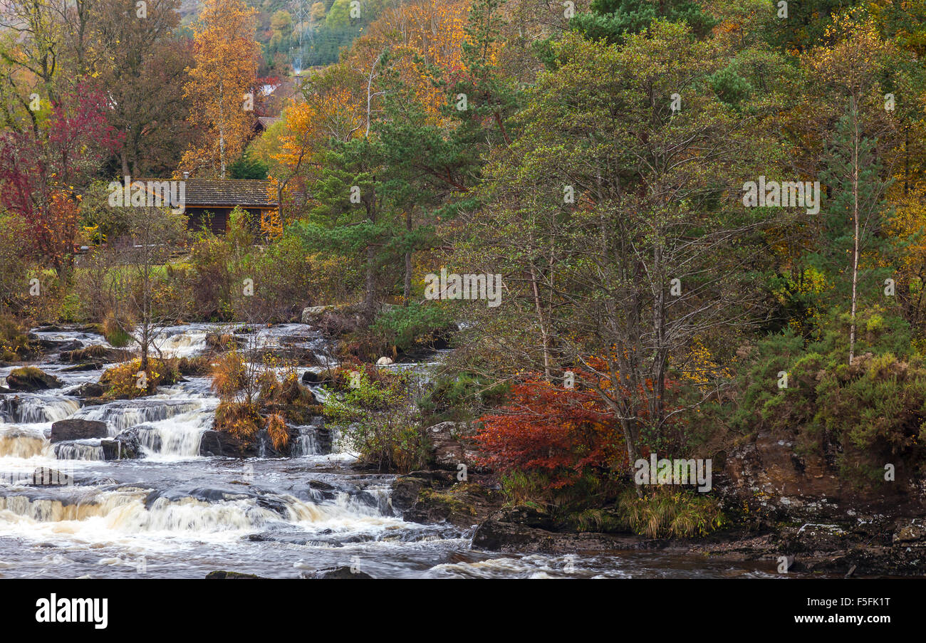 Part of the Falls of Dochart in the village of Killin in Perthshire, Scotland, with trees in autumn colours. Stock Photo