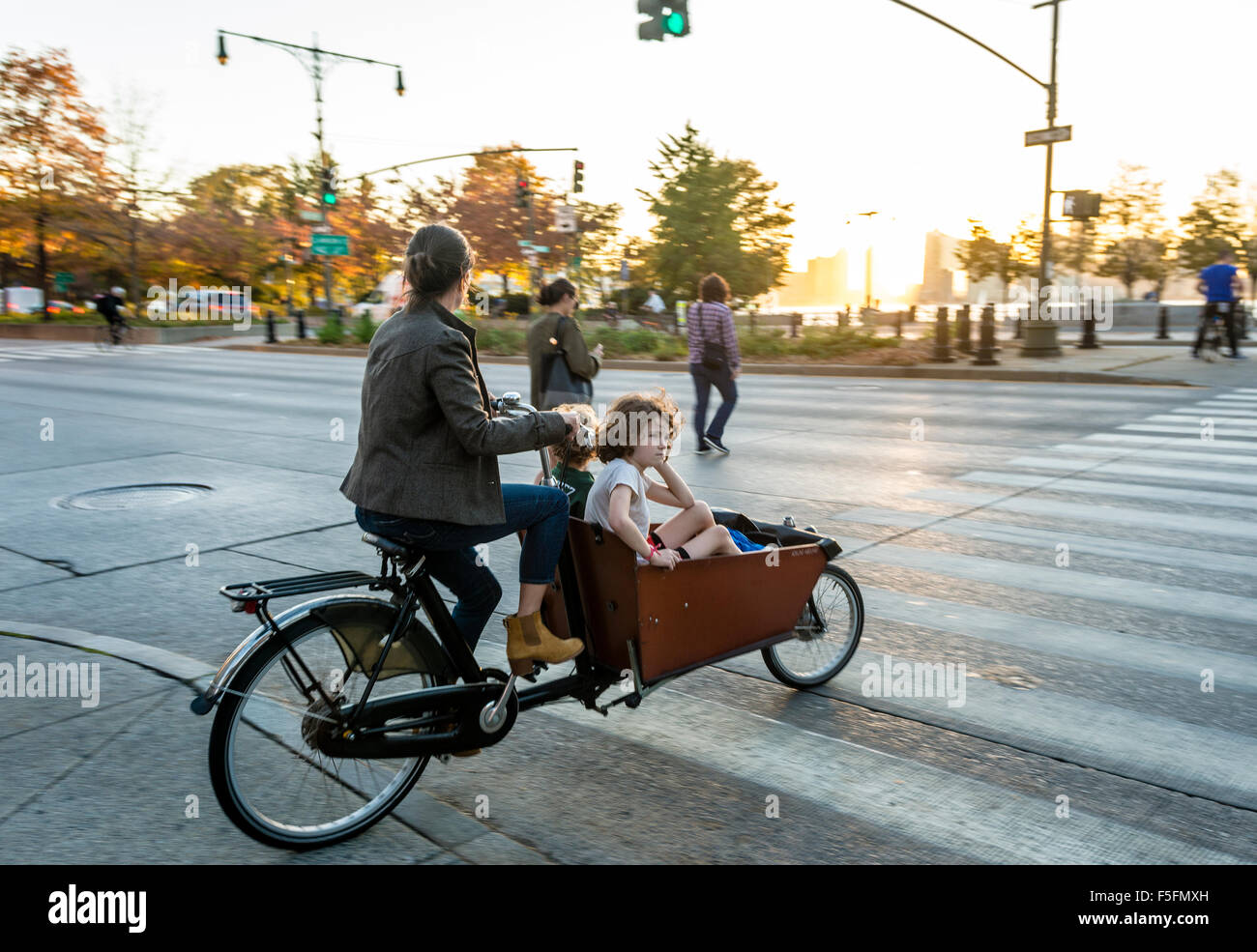 New York, NY A mother and two children riding a bakfiet (Dutch Cargo Bike )  cross the West Side Highway into Hudson River Park Stacy Walsh Rosenstock/Alamy Stock Photo