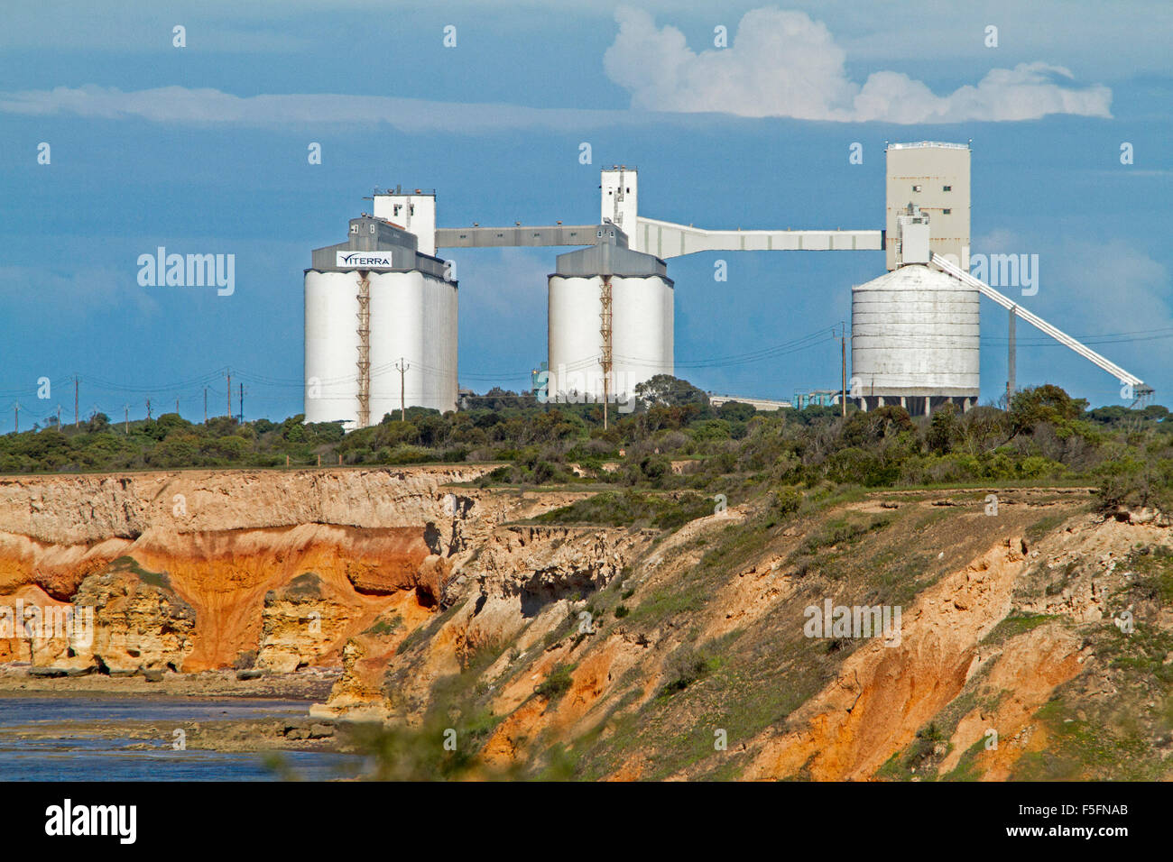 Huge white grain silos at Port Giles, on red coastal cliffs beside