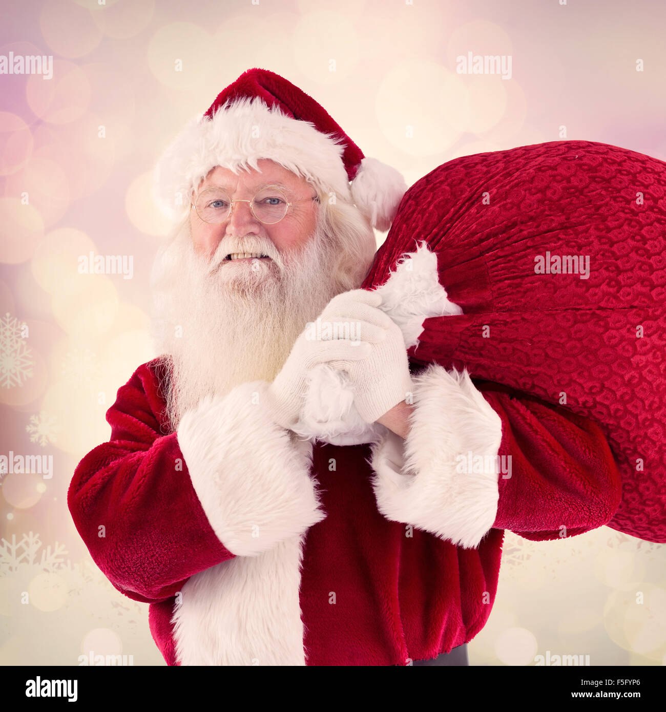 Composite image of santa carries his red bag and smiles Stock Photo - Alamy
