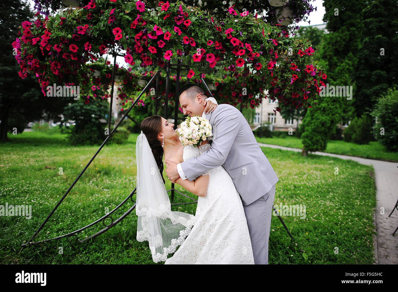 Happy wedding couple on backqround red flowers Stock Photo - Alamy