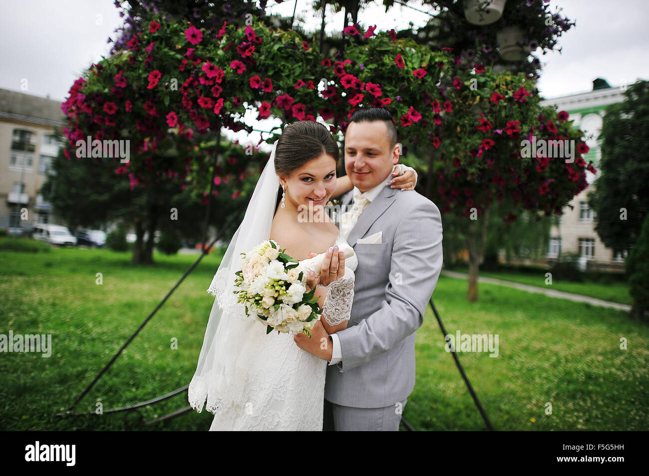 Happy wedding couple on backqround red flowers Stock Photo - Alamy