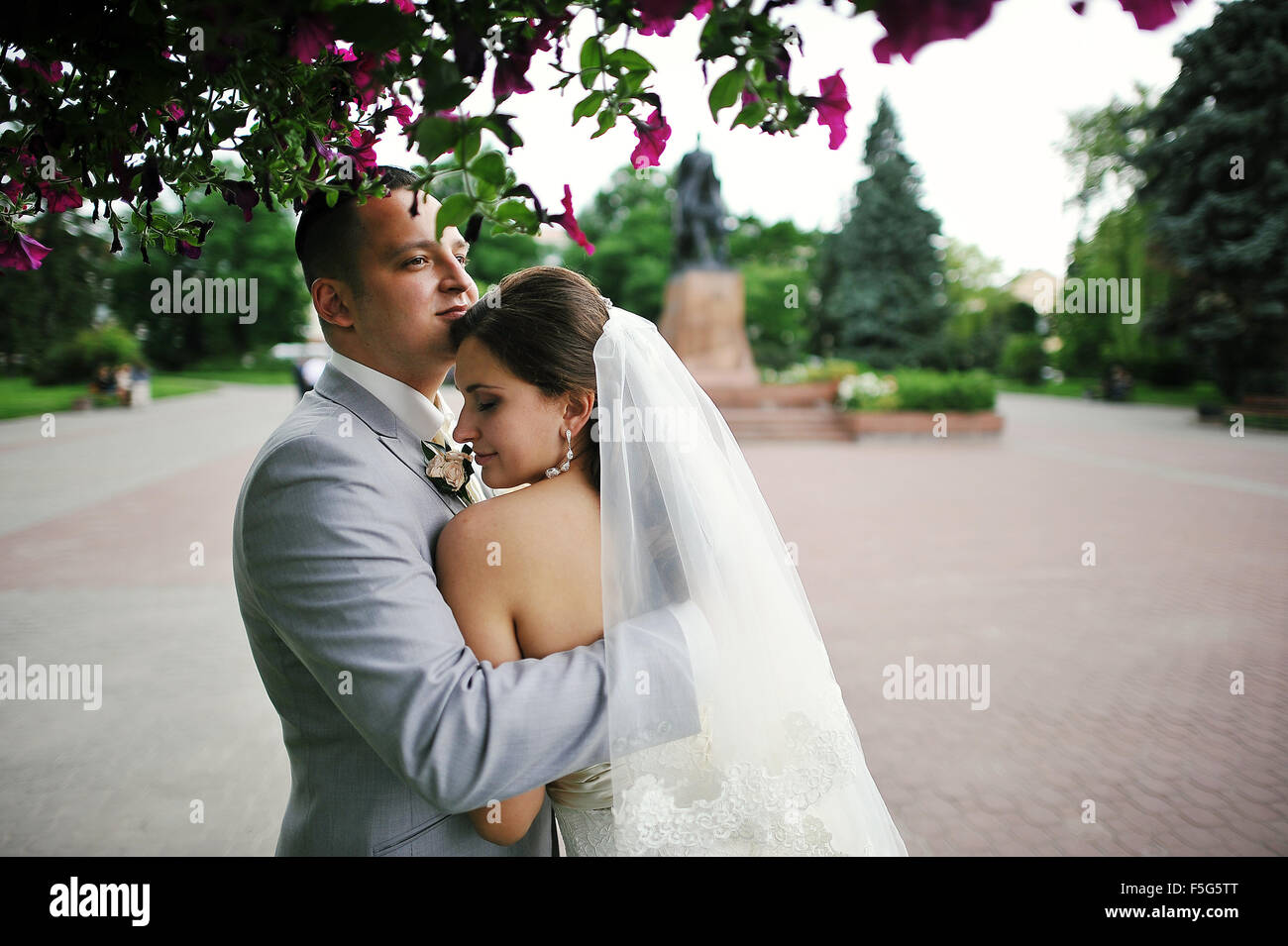 Happy wedding couple on backqround red flowers Stock Photo - Alamy