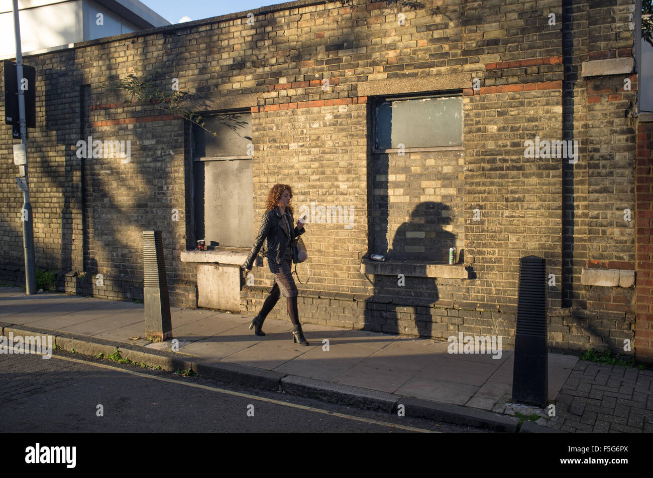A woman walking home on an autumn evening in Islington, North London Stock Photo