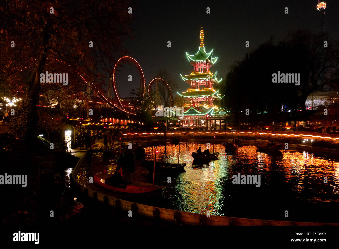 The Dragon Boats in the lake in front of the Japanese Tower restaurant and rides at night in Tivoli gardens on a dark Halloween Stock Photo