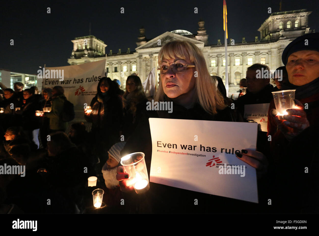 HANDOUT - A Handout datedd 3 November 2015 shows people taking part in a demonstration with candles burning outside the Reichstag in Berlin, Germany. They are burning as part of a memorial event of the international organisation Doctors without Borders, visible is a banner reads 'Even war has rules'.   A month after the attack on the Doctors without Borderds hospital in the northern Afghan city of Kunduz, organisers among the victims reiterated demand for an independent investigation. Photo:Stephanie Pilick/Ärzte ohne Grenzen/dpa      ATTENTION MUST BE USED WITH MANADATORY CREDIT: Stephanie Pi Stock Photo