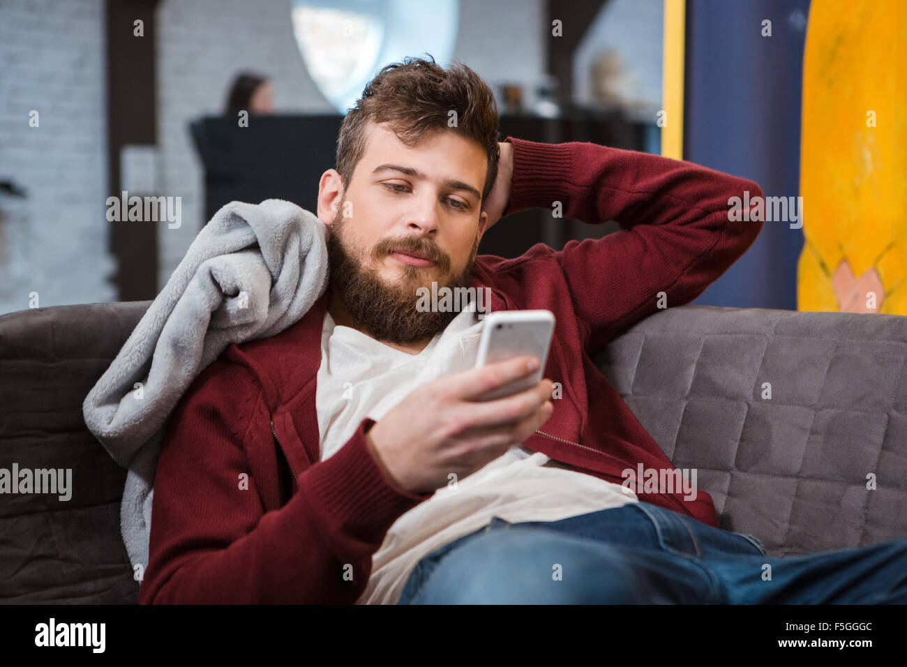 Relaxed Young Handsome Attractive Man Lying Grey On Sofa And Using