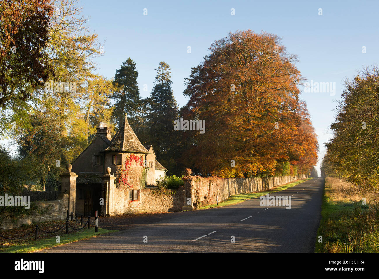 Stowell park estate gate house and beech trees with autumn foilage in the cotswold countryside. Gloucestershire, England. Stock Photo