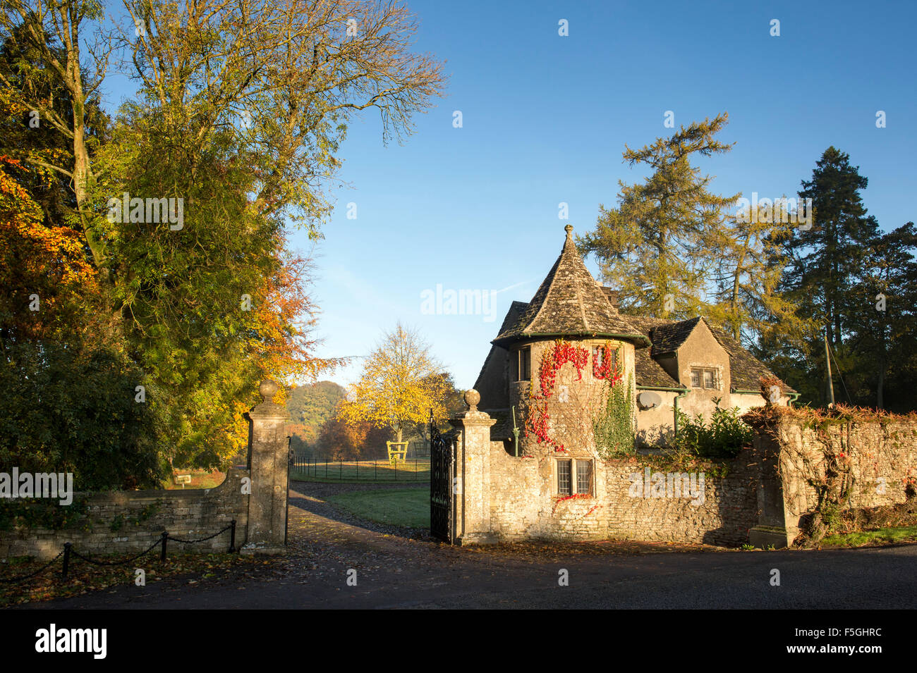 Stowell park estate gate house and beech trees with autumn foilage in the cotswold countryside. Gloucestershire, England. Stock Photo