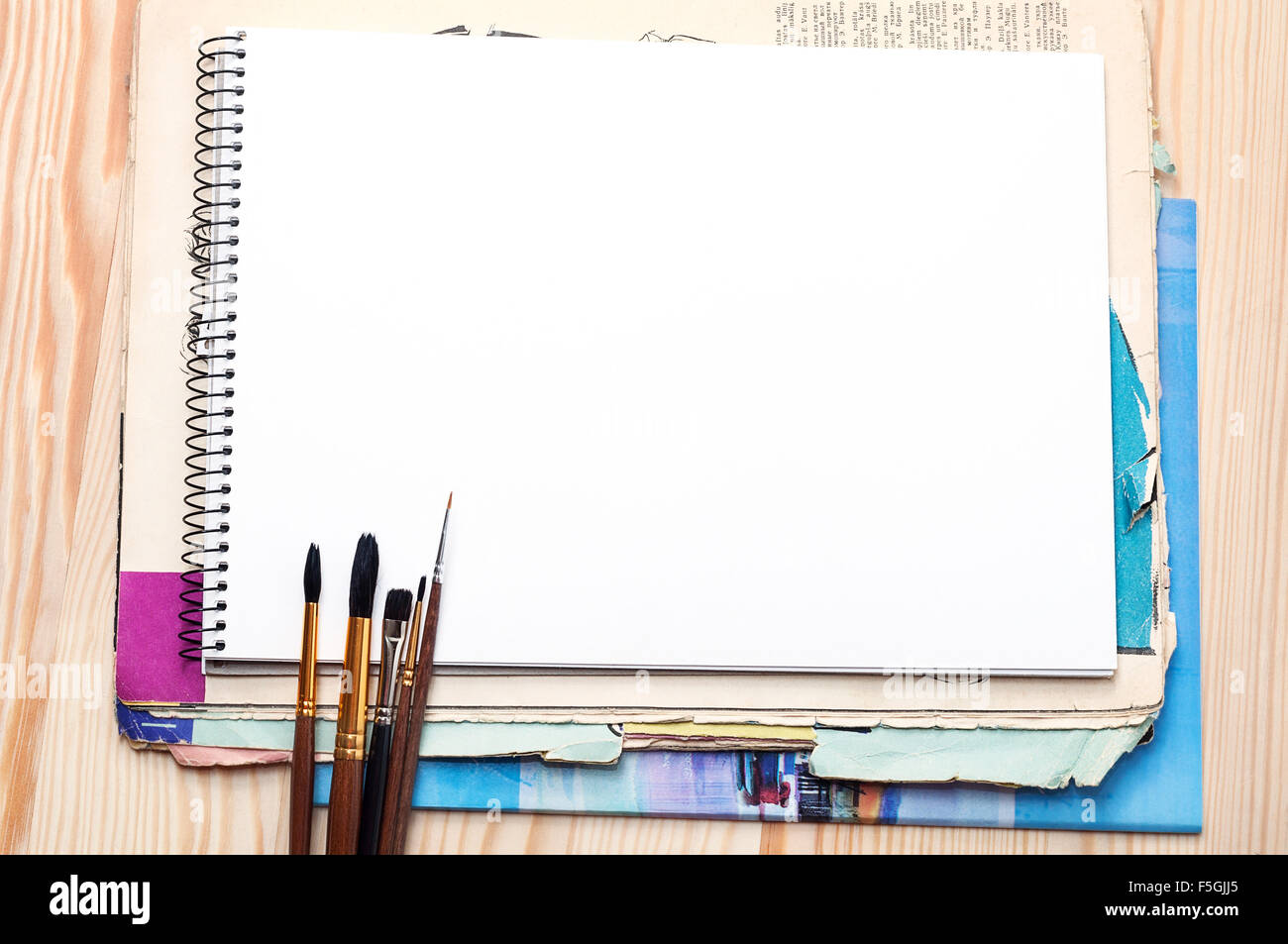 Blank notebook, brushes and old paper sheet on a wooden surface Stock Photo