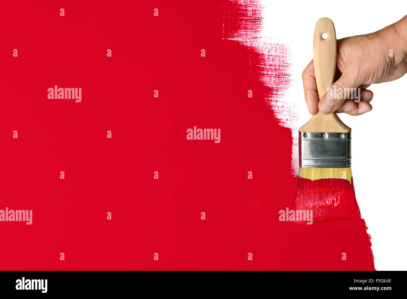 Man's hand using paintbrush with red paint on wall Stock Photo
