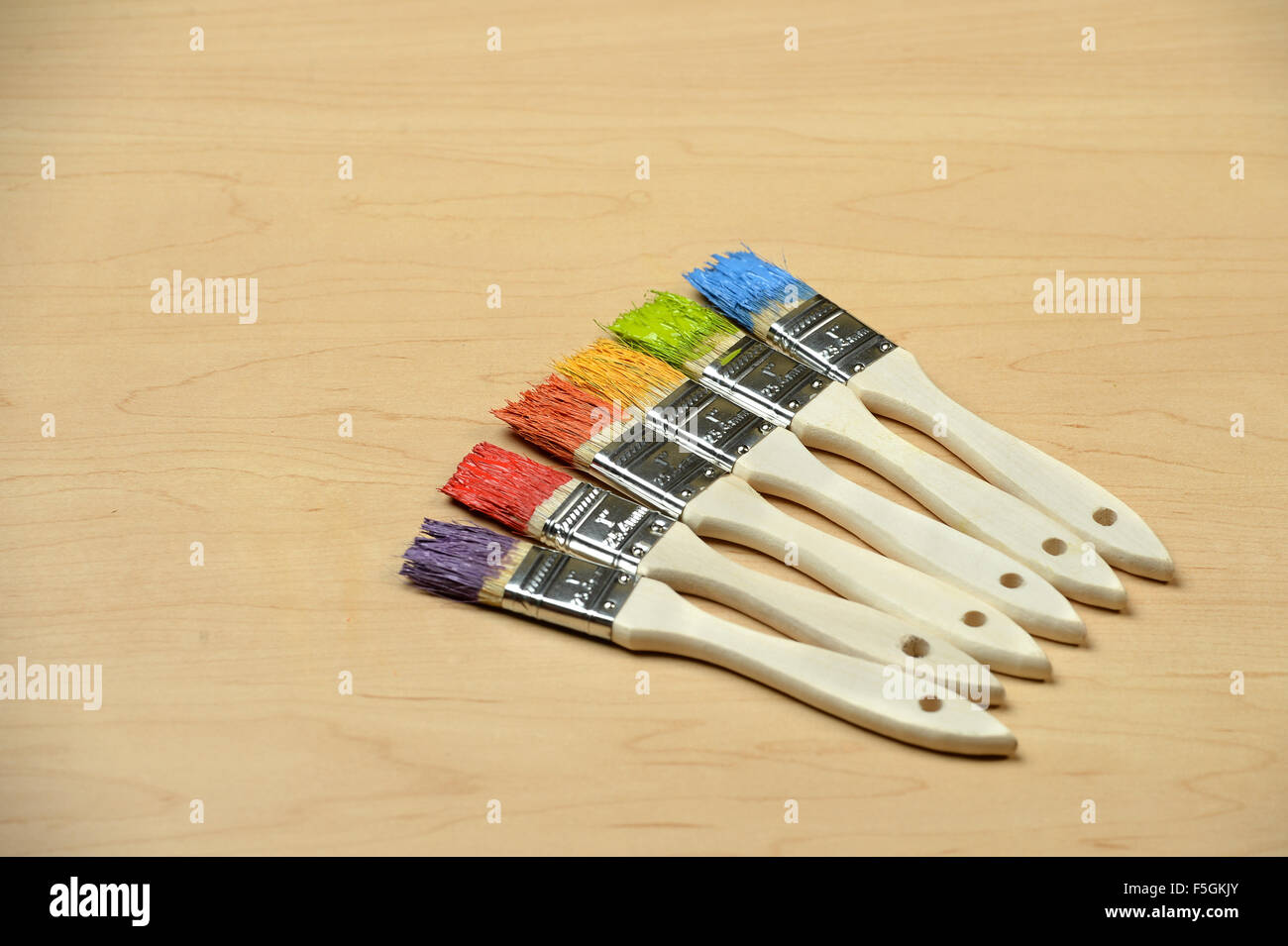 Paintbrushes with different color paint over table - With copy space Stock Photo