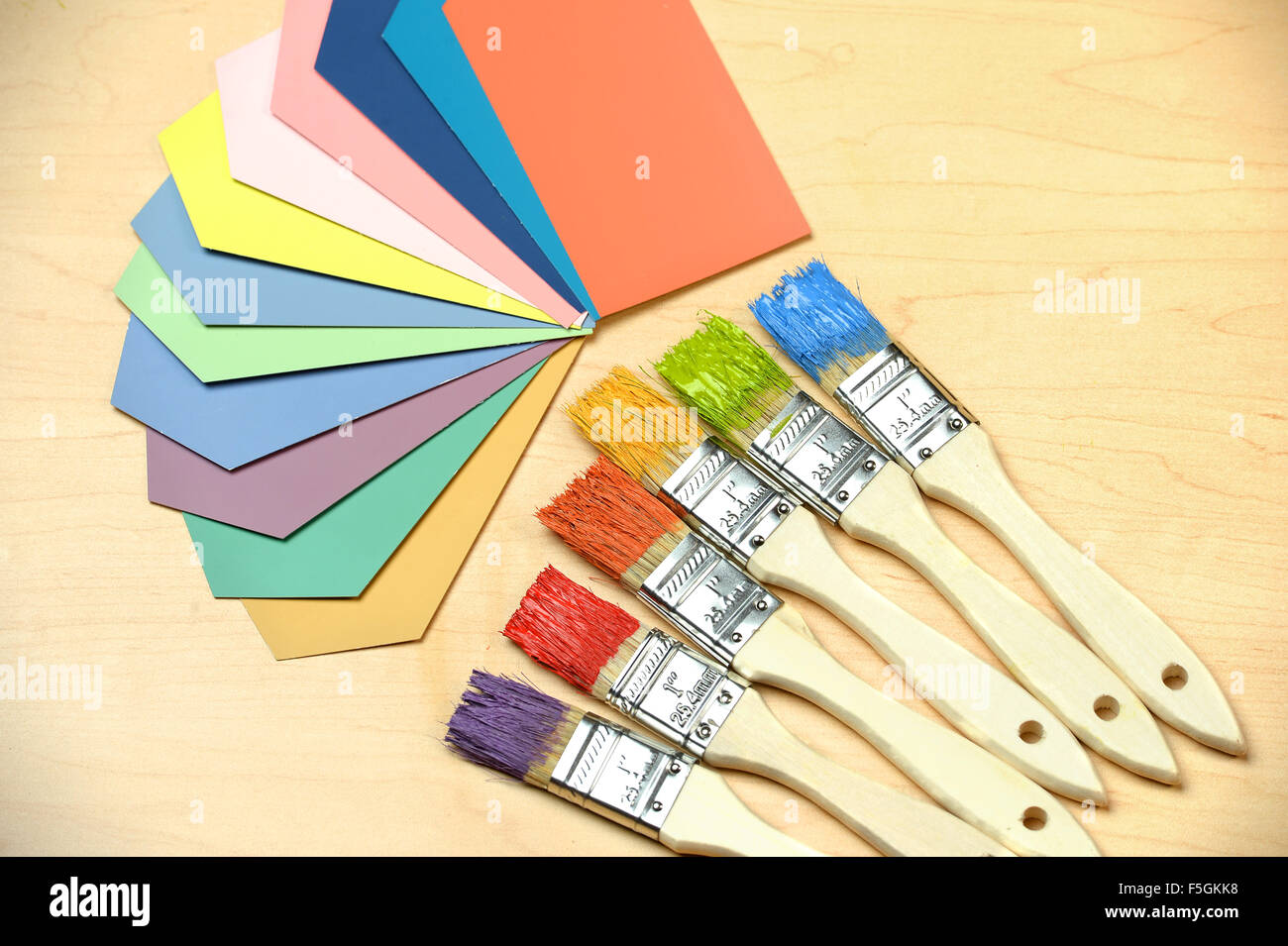 Assortment of color samples and paintbrushes over table Stock Photo