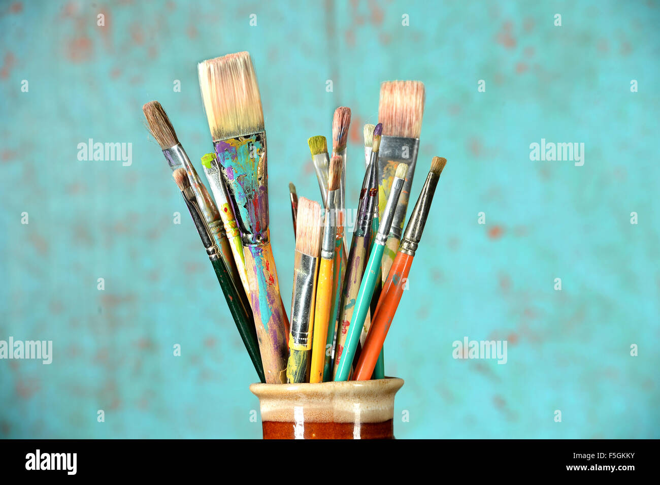 Artist paintbrushes in a jar over colorful background Stock Photo