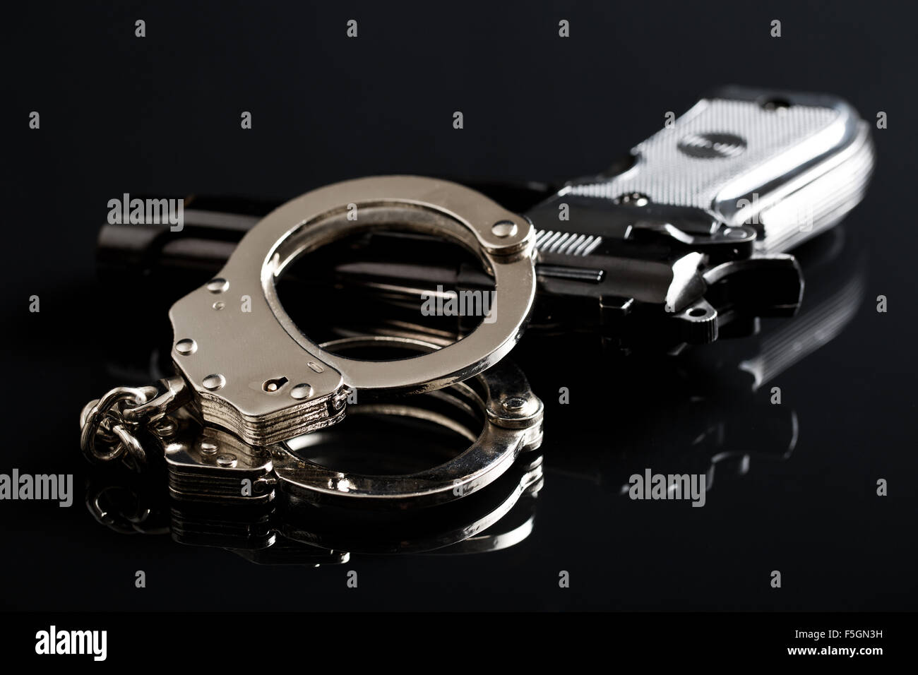 handcuffs and handgun on black background Stock Photo