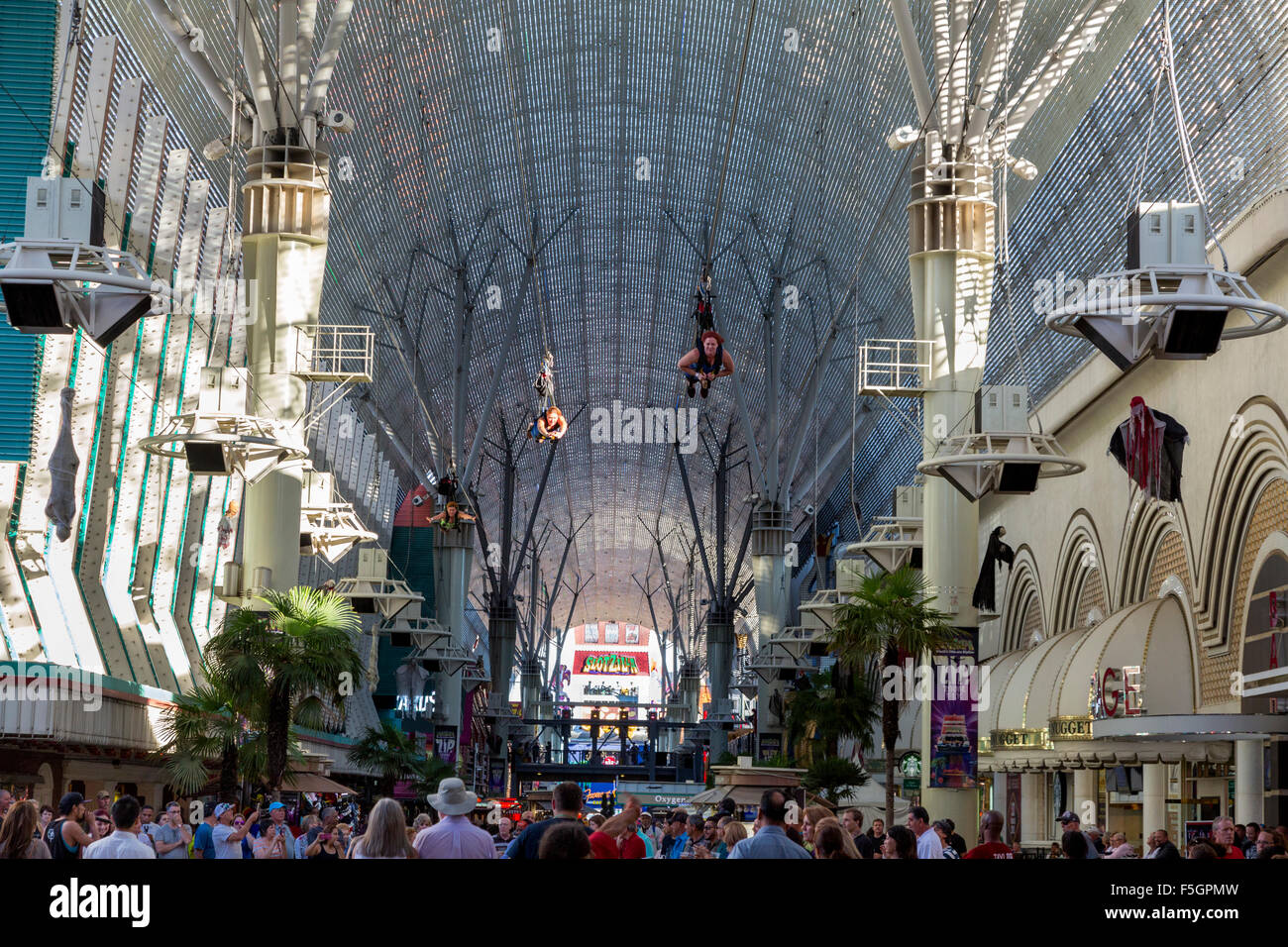 Las Vegas, Nevada.  Fremont Street.  Three Zoomline Riders Fly above the Crowds on the 1750-foot Zip Line. Stock Photo