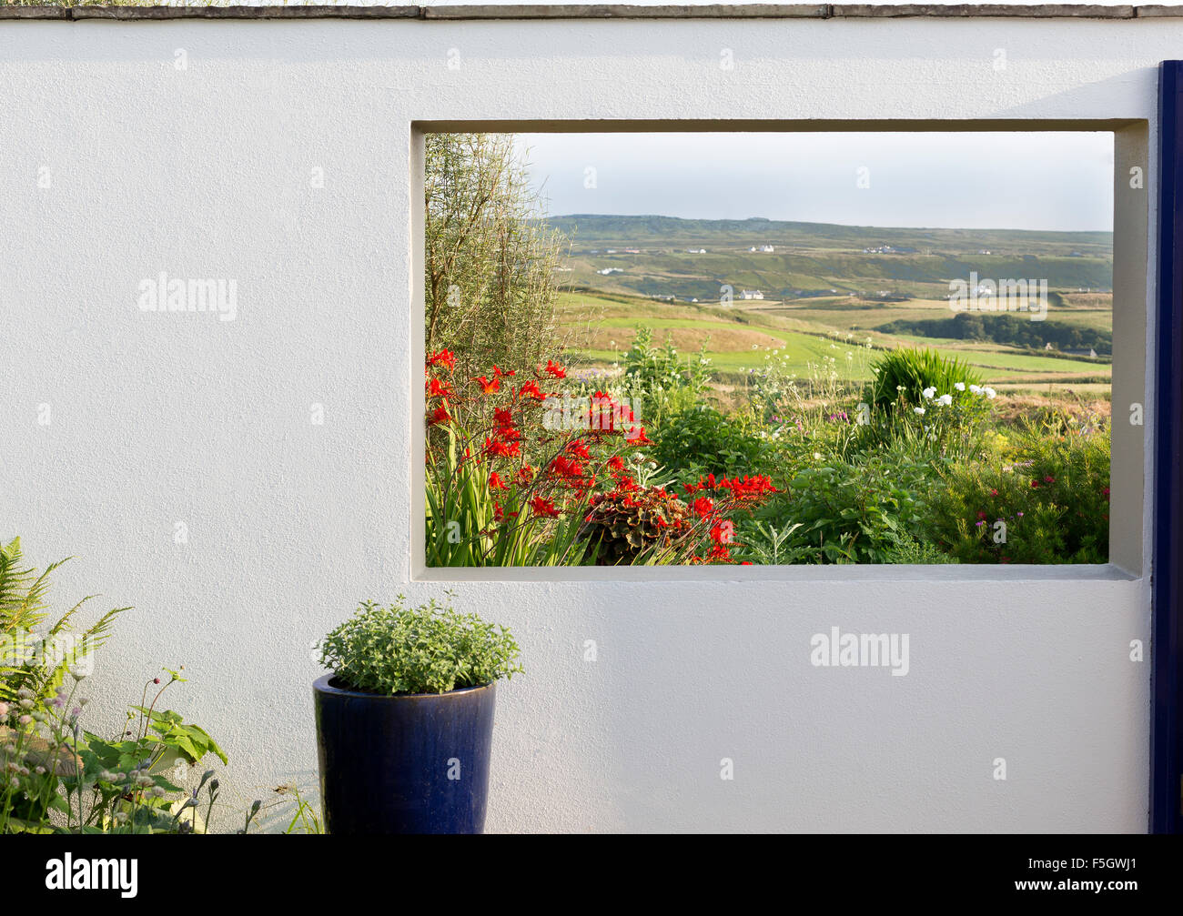 Irish landscape garden with view of countryside in opening on wall Stock Photo