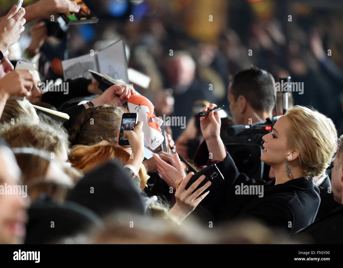 Schauspielerin Jennifer Lawrence (r) kommt am 04.11.2015 in Berlin zur Weltpremiere von 'Die Tribute von Panem - Mockingsjay Teil 2' in das Kino Cinestar und schreibt Autogramme. Foto: Jens Kalaene/dpa    (c) dpa - Bildfunk    Stock Photo