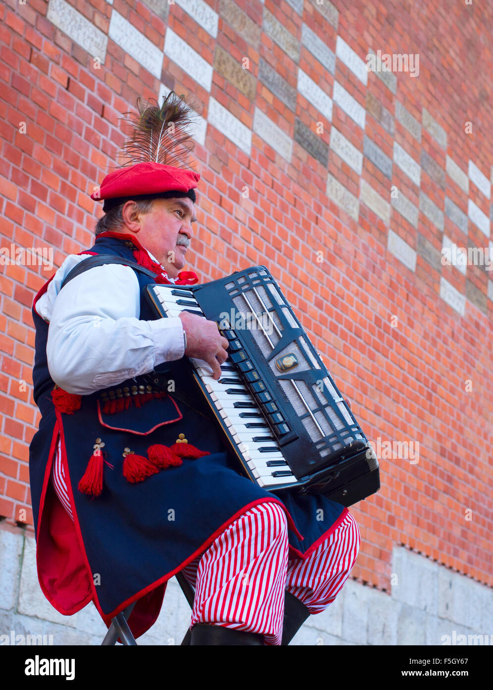 Street musician wore in traditional Poland dress playing on the street of Krakow. Stock Photo