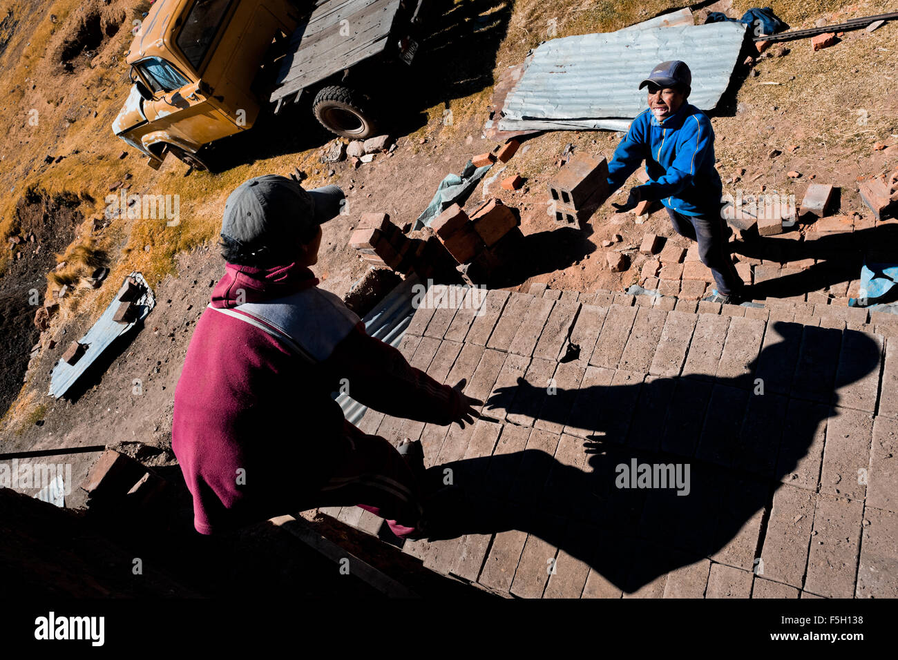 Peruvian boys pile raw bricks aside a kiln at a brick factory in the outskirts of Puno, Peru. Stock Photo