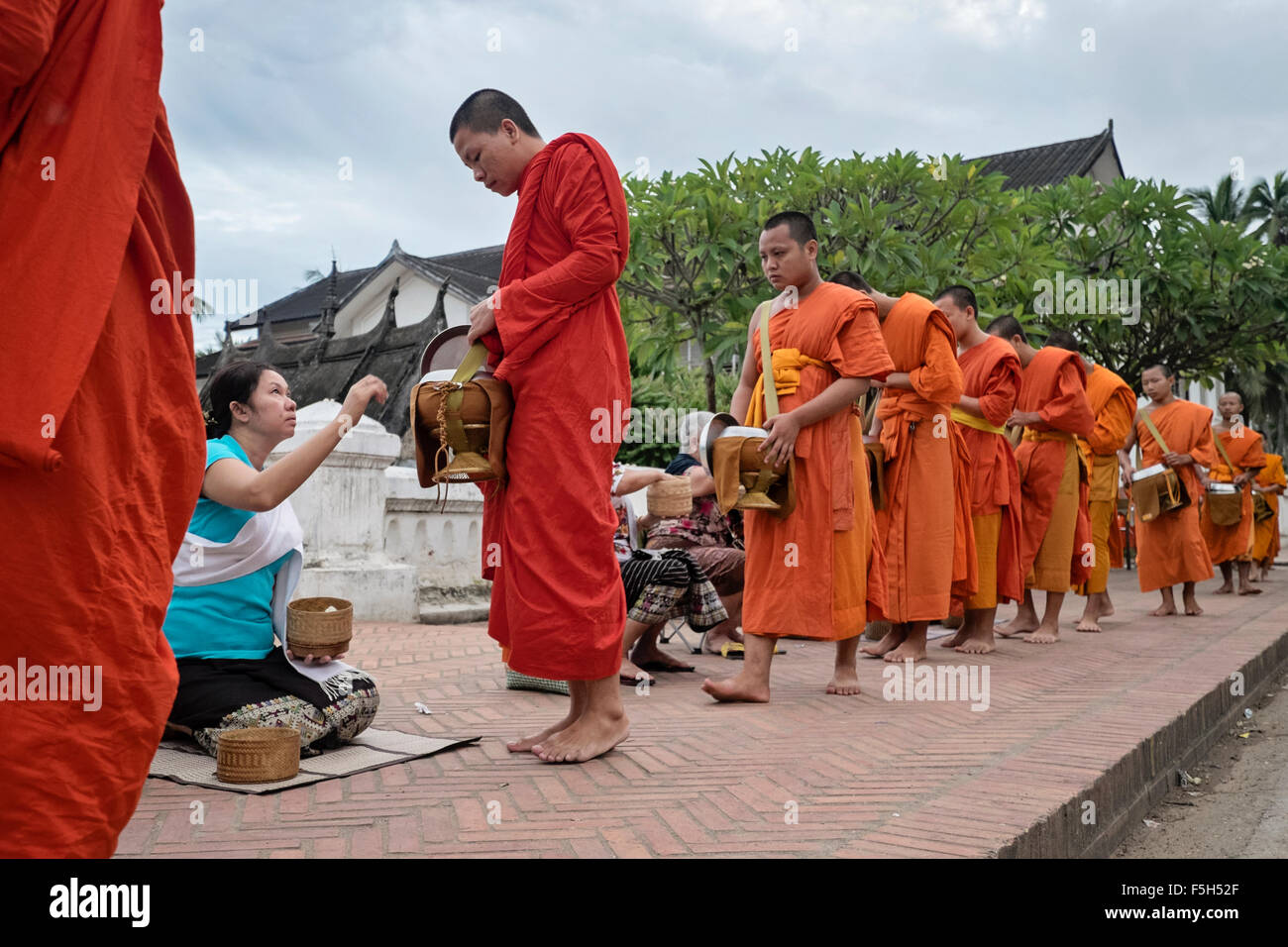 Worshipers give alms and food to Buddhist monks in Luang Prabang, Laos Stock Photo