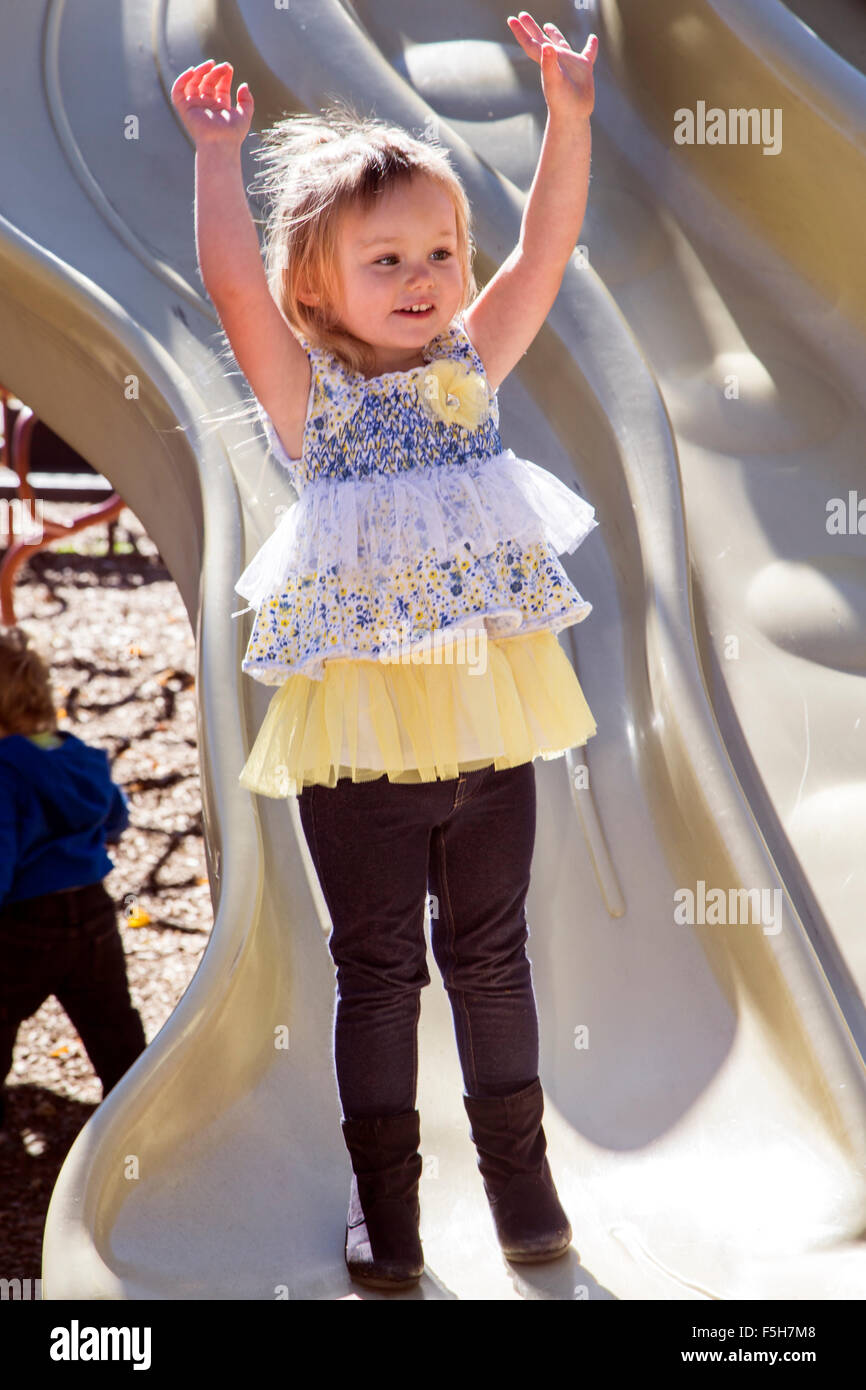 Four year old little girl playing outside on a jungle gym in a park