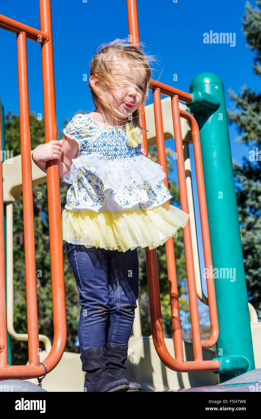 Four year old little girl playing outside on a jungle gym in a park