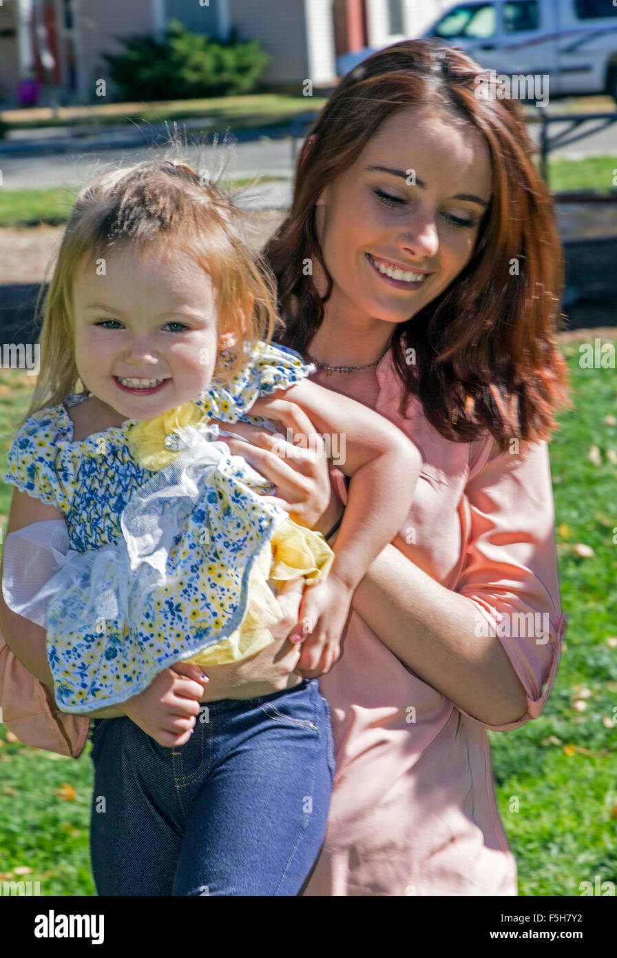 Beautiful mother holding cute young daughter, town park Stock Photo