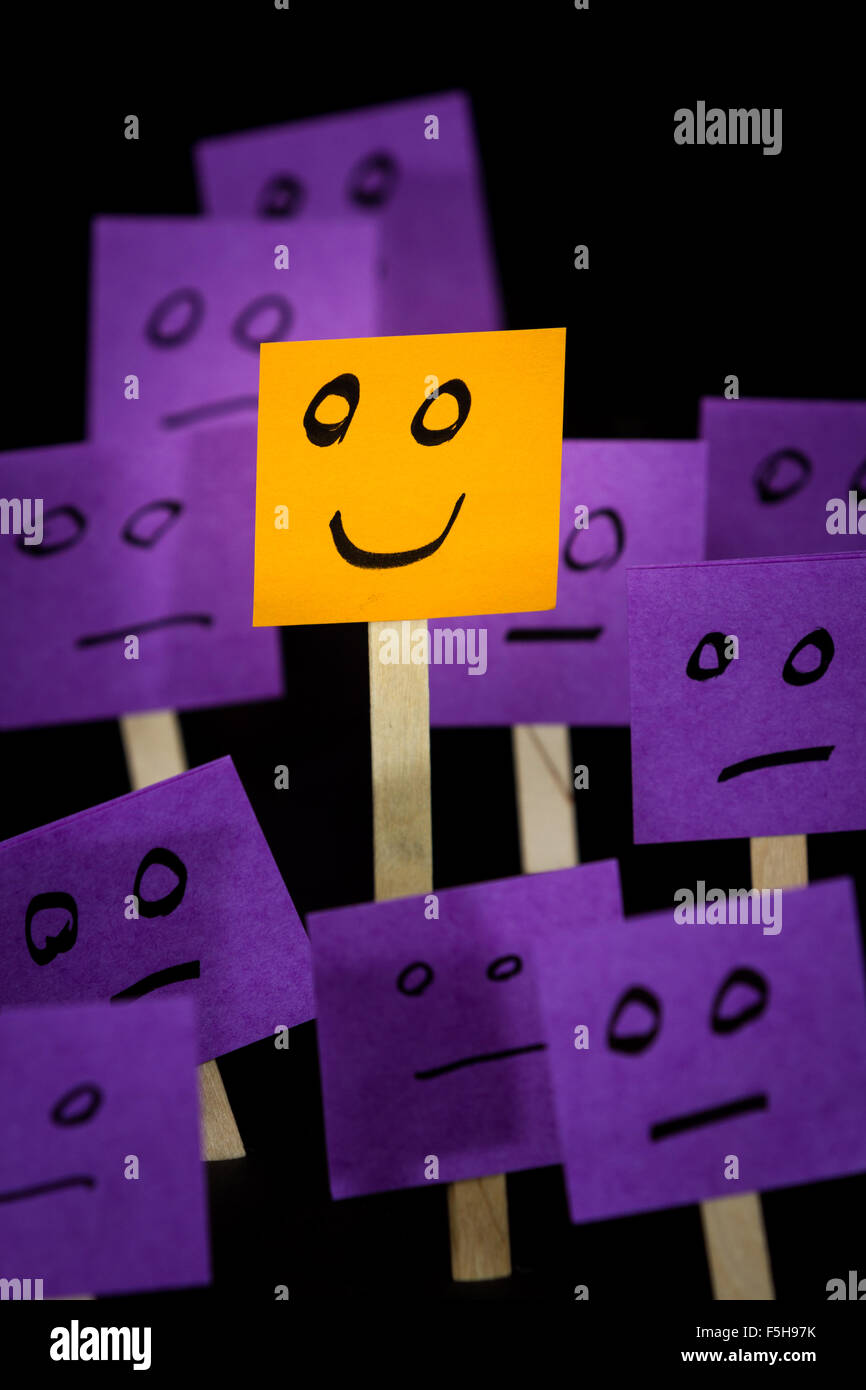 conceptual image using sticky notes with hand drawn faces on them isolated on a black background Stock Photo