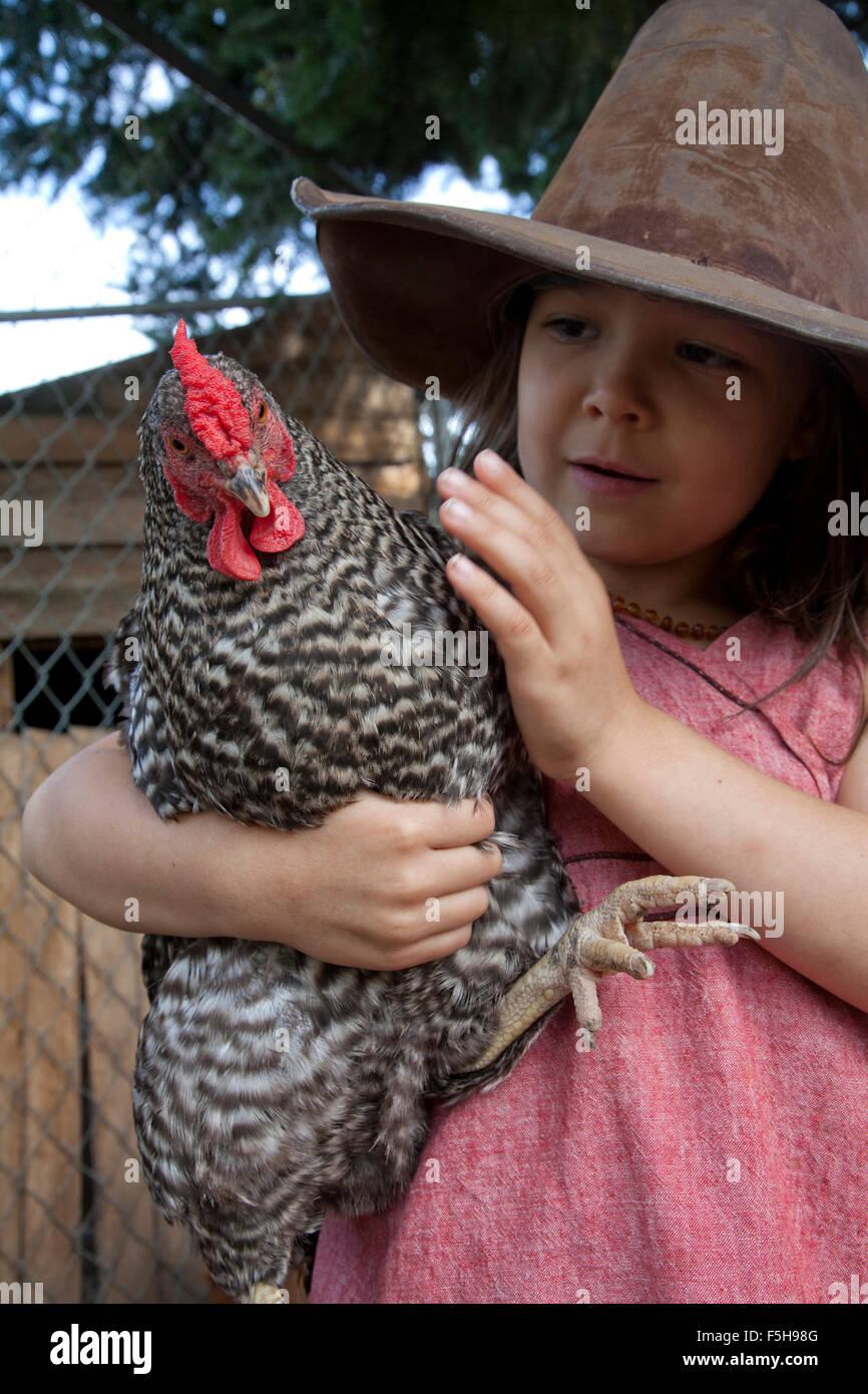 young girl with big hat holds black and white hen Stock Photo