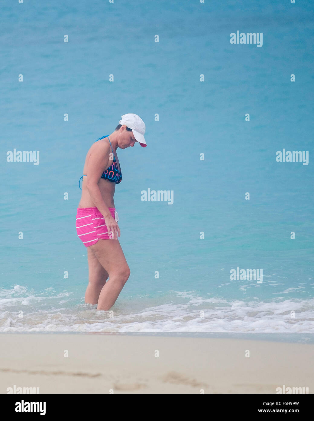 A Caucasian woman in a two-piece bathing suit wades in the Caribbean sea. Stock Photo