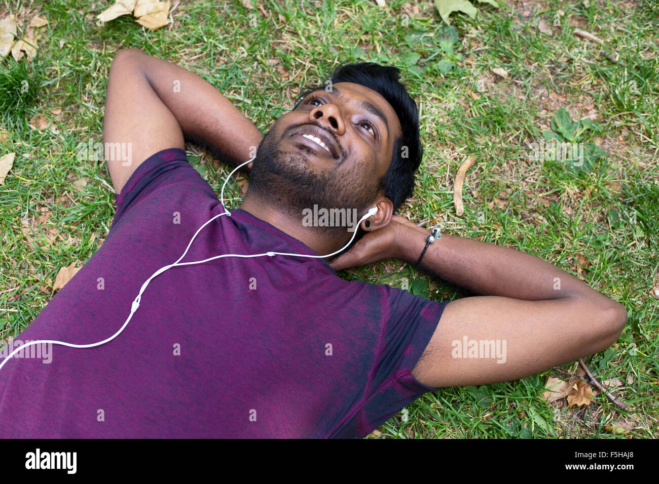 young indian man relaxing in the park listening to music Stock Photo