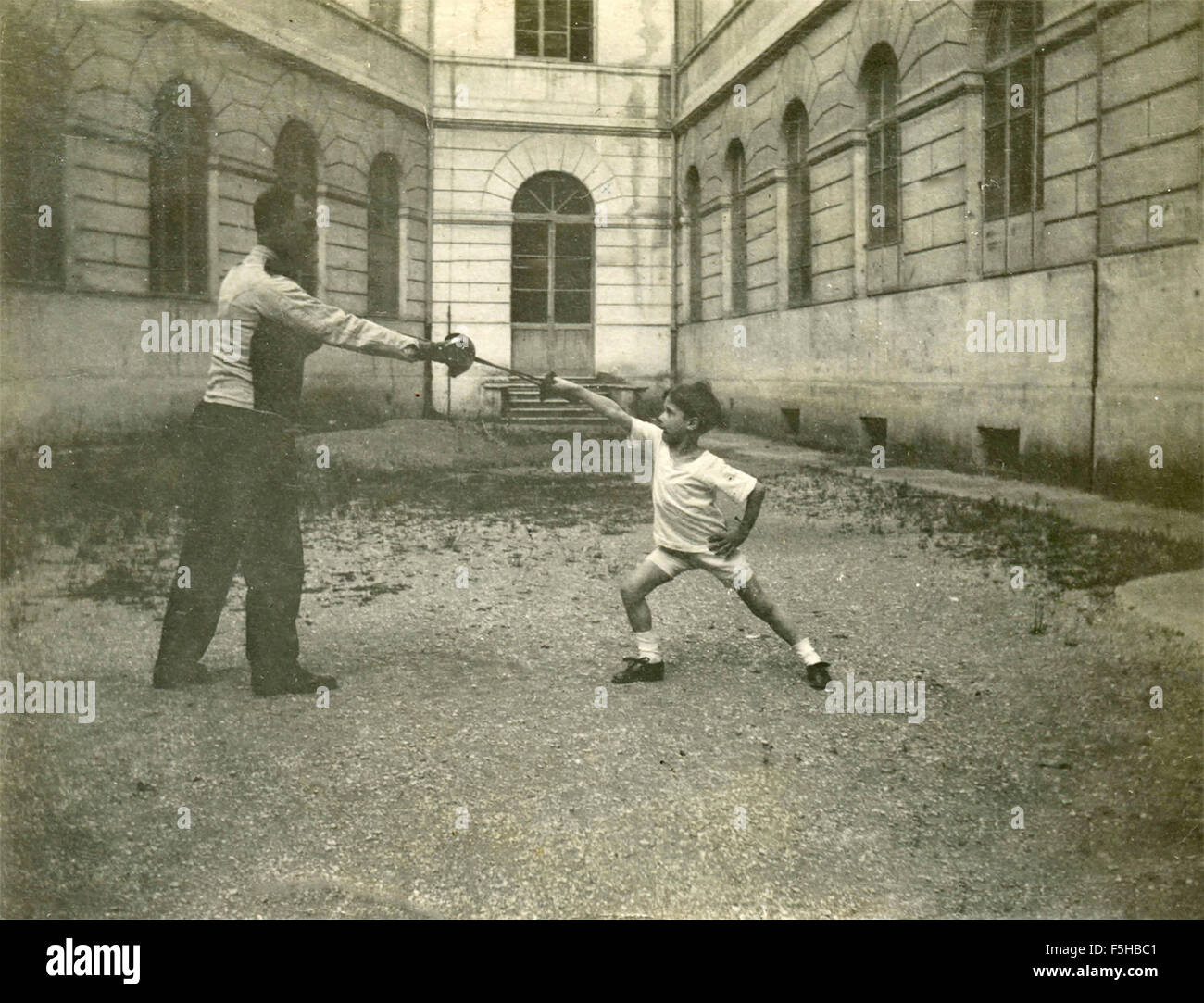 Child pulls fencing with his father, Italian Stock Photo