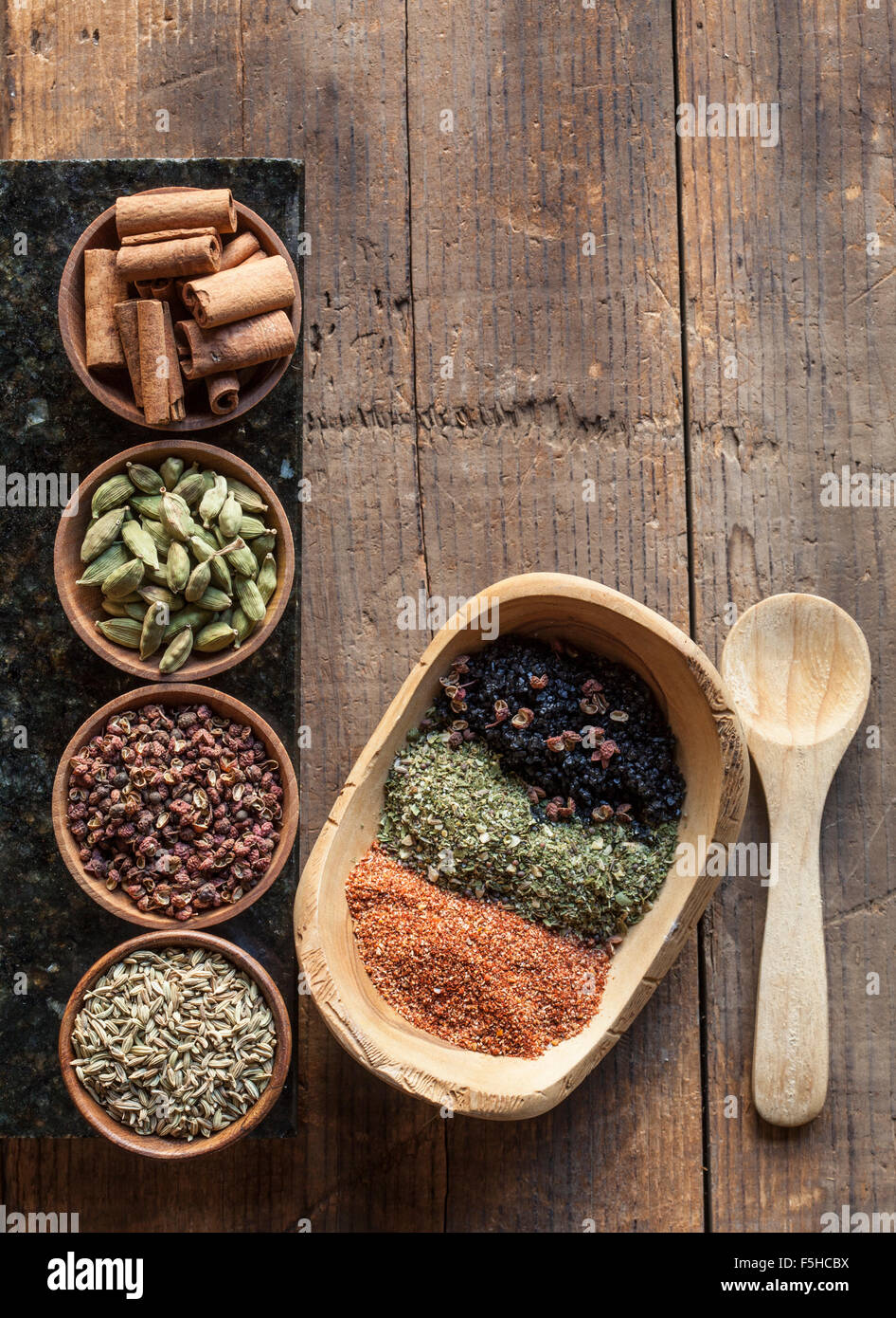 Various spices in small wooden bowls with spice mixtures on rustic wood with a wooden spoon Stock Photo