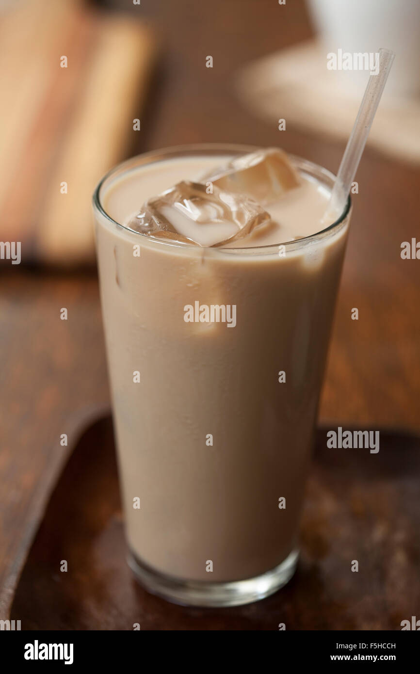Iced chai in tall glass with ice and straw on wood Stock Photo