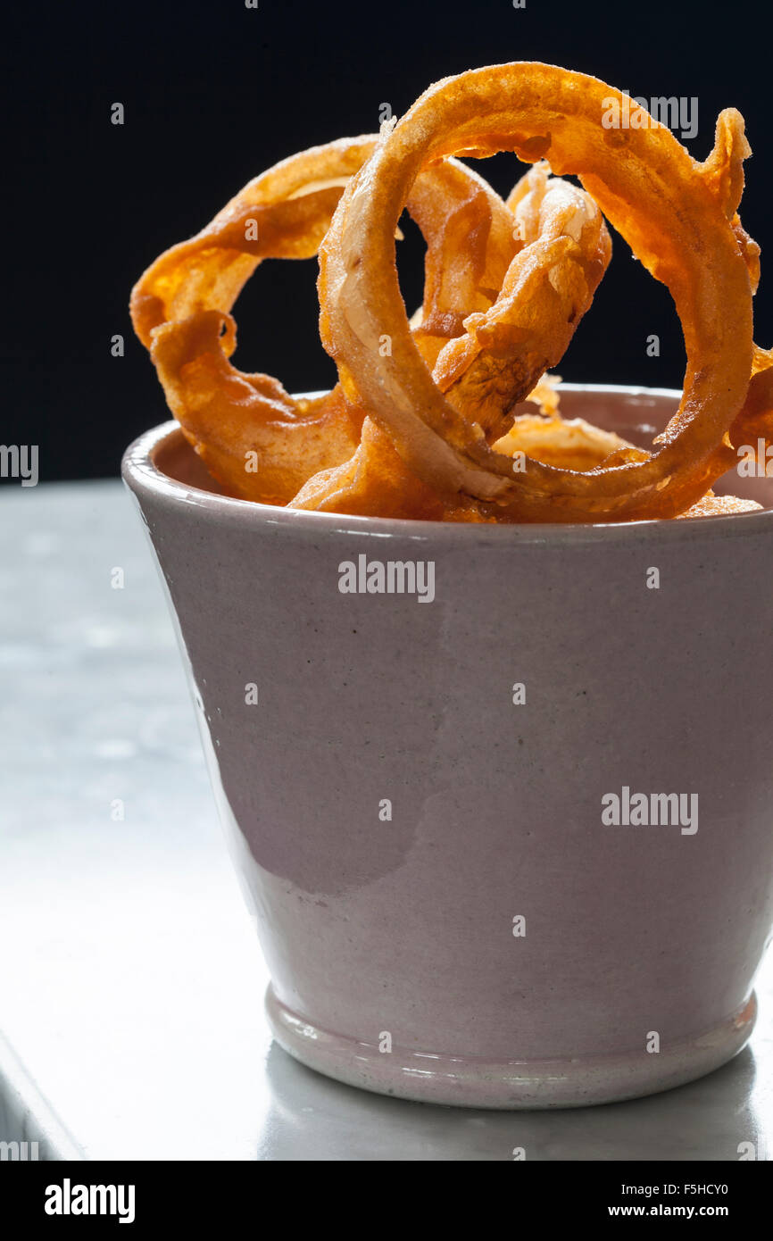 Backlit onion rings in tall off-white bowl Stock Photo