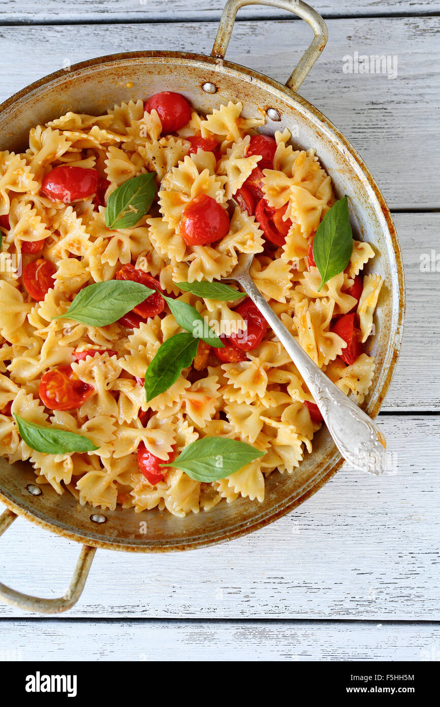 pasta with tomatoes and basil in old pan Stock Photo