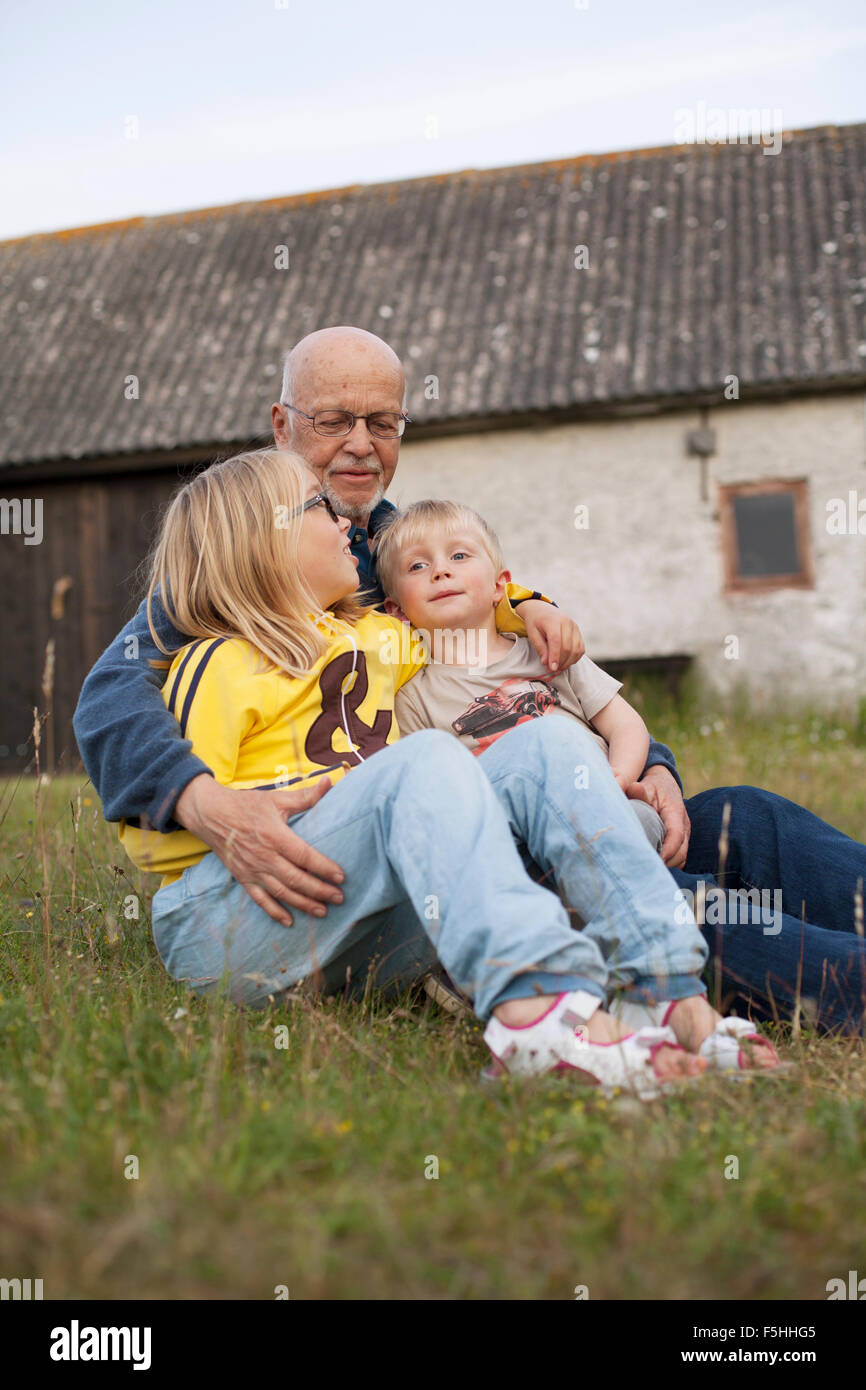 Sweden, Gotland, Faro, Grandfather talking with his grandchildren (2-3, 10-11) Stock Photo