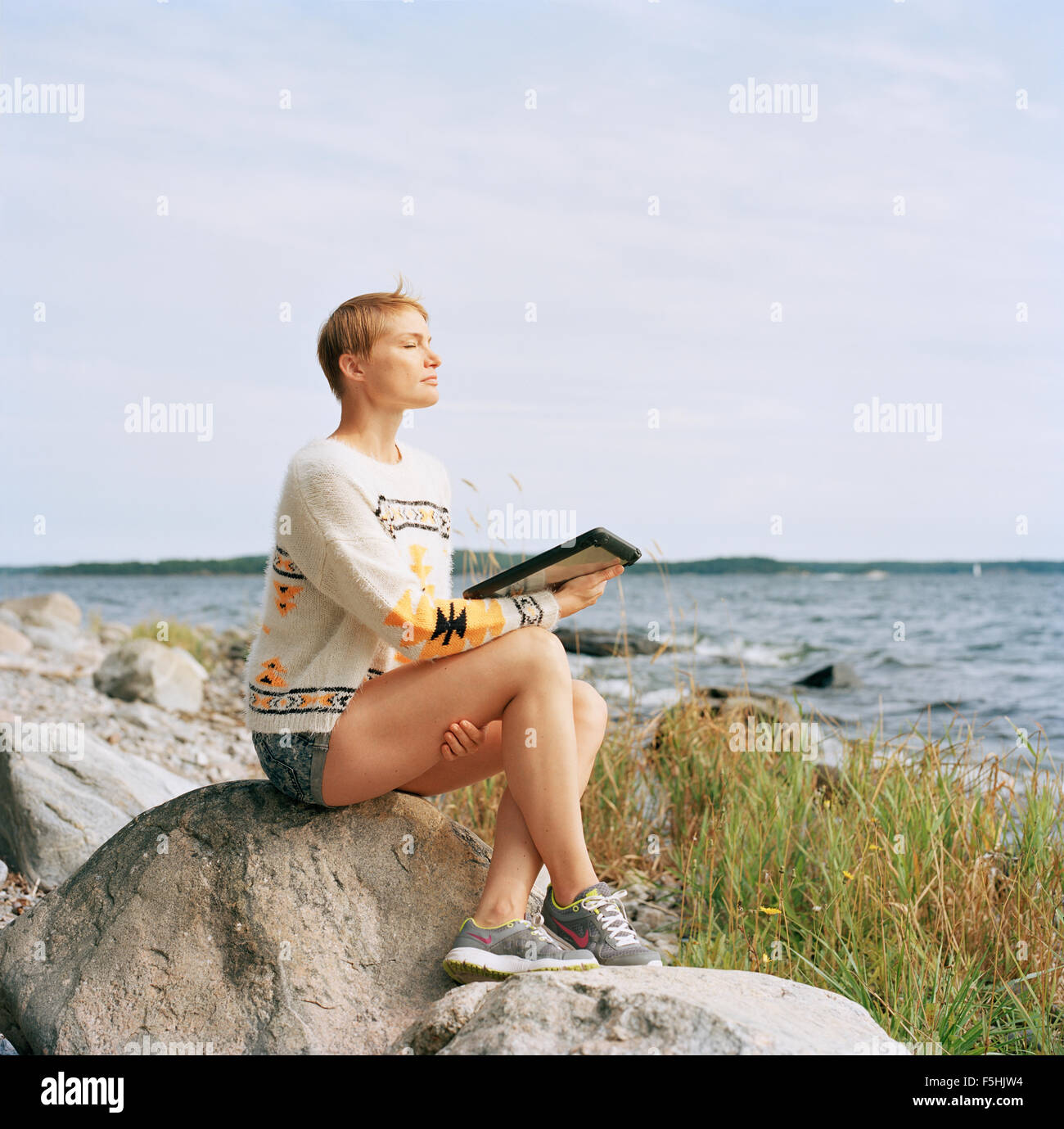 Sweden, Sodermanland, Galo, Woman using tablet pc at beach Stock Photo