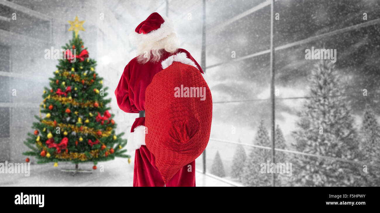 Composite image of santa is holding his bag in one hand Stock Photo - Alamy