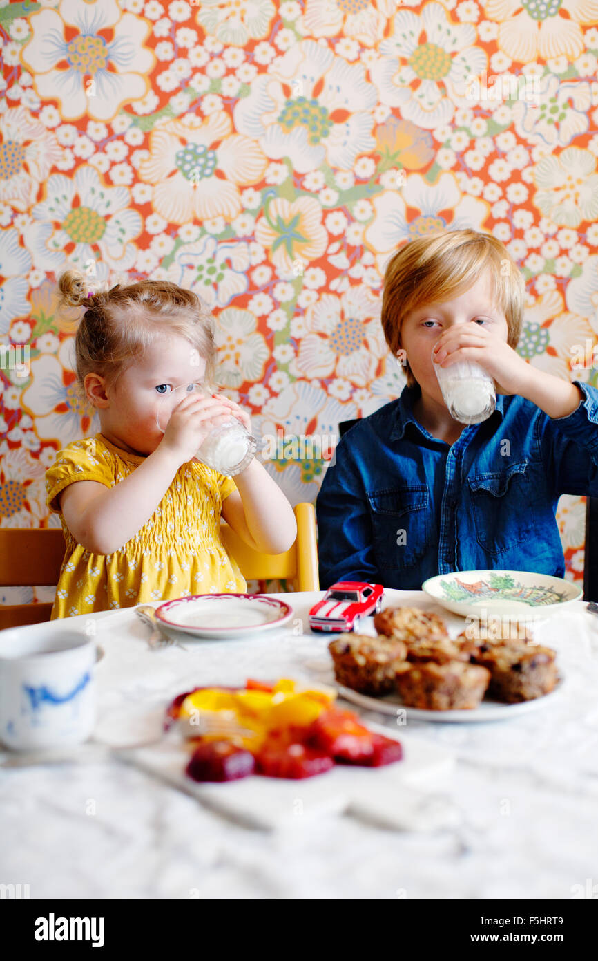 Sweden, Boy (10-11) and girl (2-3) drinking milk Stock Photo